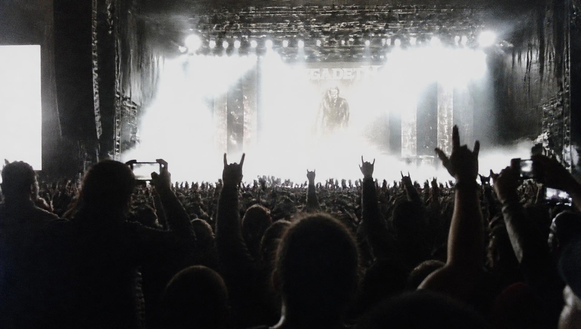 Público con las manos en alto frente a un escenario iluminado en un concierto en Bogotá
